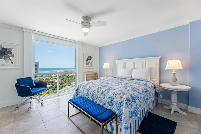 bedroom with light tile patterned floors, a water view, ceiling fan, a wall of windows, and baseboards