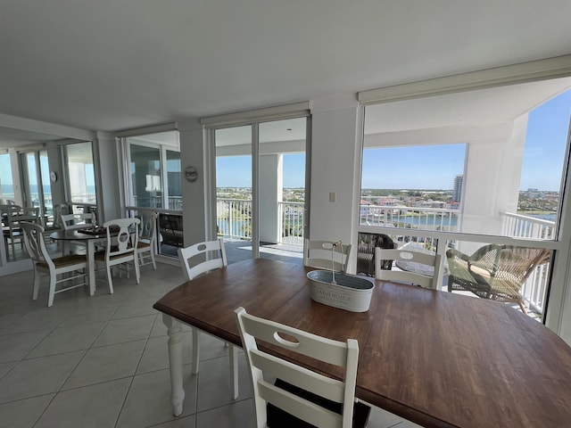 dining room with a wall of windows, a water view, and tile patterned floors