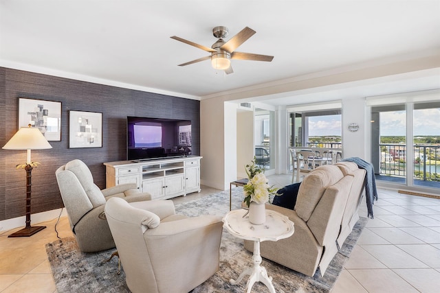 living area featuring light tile patterned floors, an accent wall, baseboards, and a ceiling fan