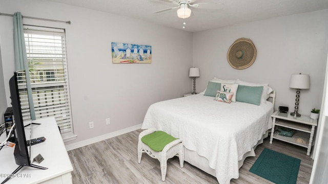 bedroom with ceiling fan, wood finished floors, and baseboards