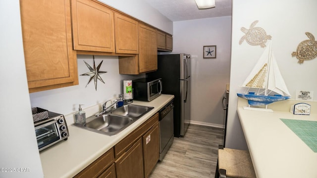 kitchen with a sink, light countertops, brown cabinetry, dishwasher, and stainless steel microwave