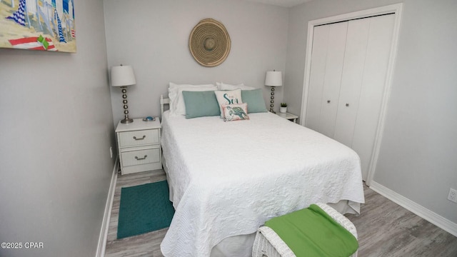 bedroom with a closet, wood finished floors, and baseboards