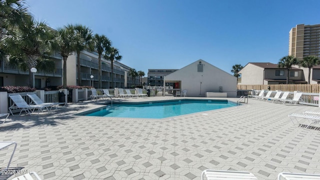 community pool with a patio area and fence