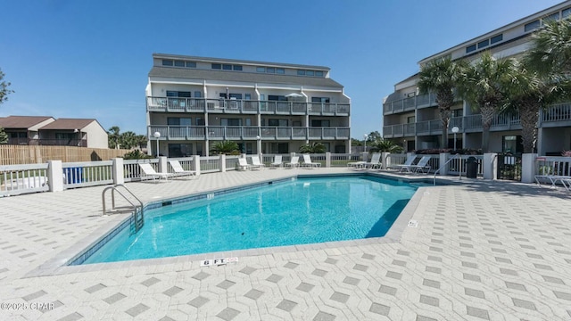 community pool with a patio and fence