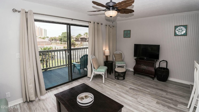 living area with a ceiling fan, light wood-type flooring, and baseboards
