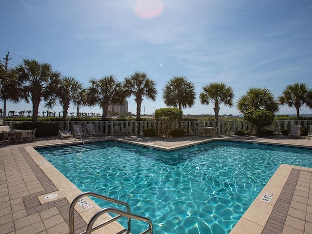 community pool featuring fence and a patio