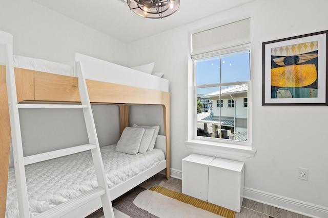 bedroom with dark wood-type flooring, a notable chandelier, and baseboards