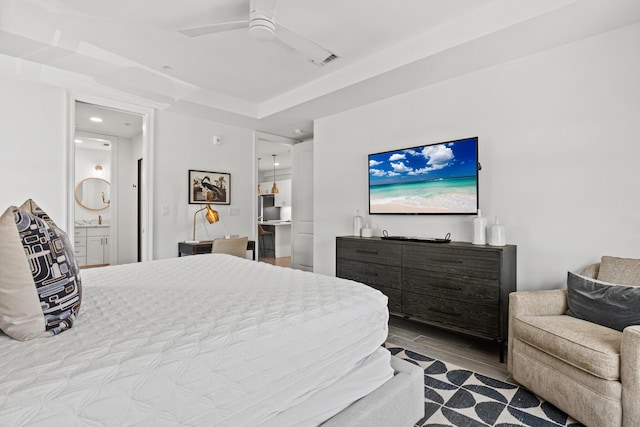 bedroom featuring visible vents, a ceiling fan, a sink, ensuite bath, and light wood-type flooring