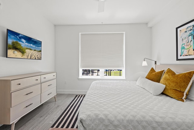 bedroom with light wood finished floors, baseboards, and a ceiling fan