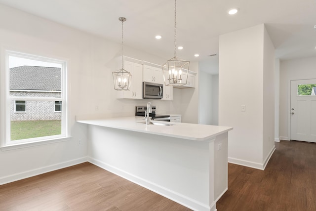 kitchen with white cabinetry, stainless steel appliances, light countertops, and dark wood finished floors