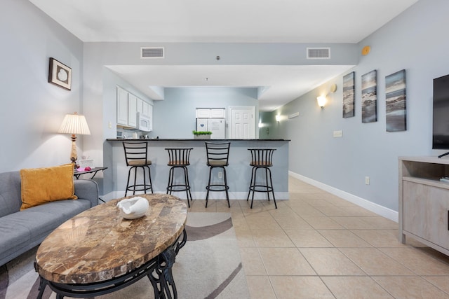 living room with a bar, light tile patterned floors, baseboards, and visible vents