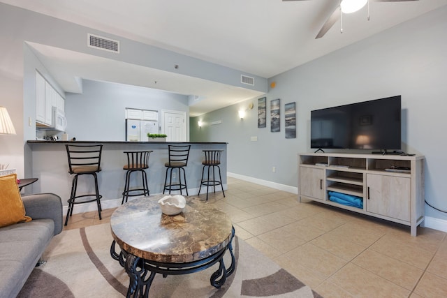 living room featuring visible vents, a bar, baseboards, and light tile patterned floors