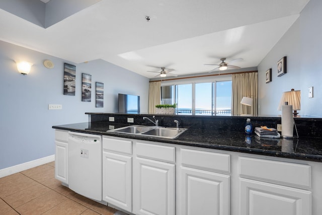 kitchen featuring white cabinets, dark stone countertops, white dishwasher, a sink, and light tile patterned flooring