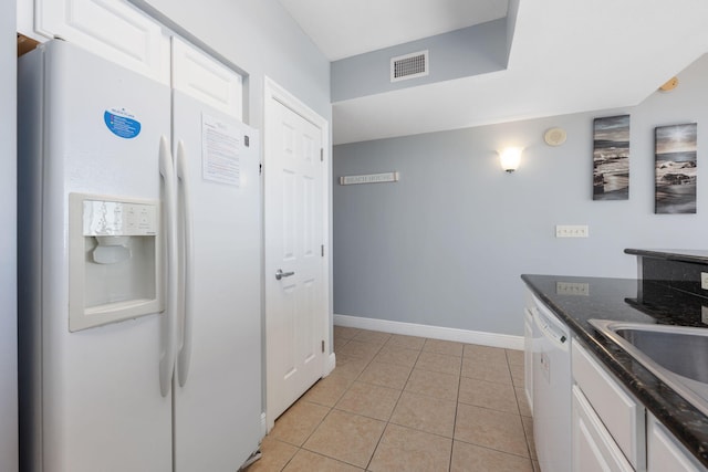 kitchen with light tile patterned floors, visible vents, white cabinets, white appliances, and baseboards