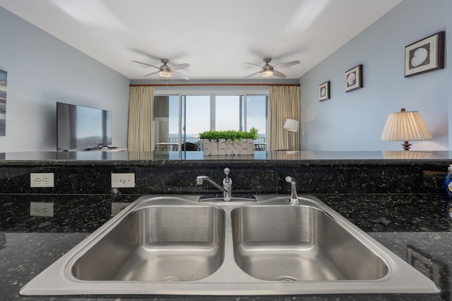 kitchen featuring dark stone counters, a sink, and open floor plan