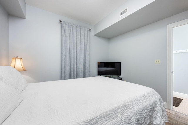 bedroom featuring wood finished floors, visible vents, and baseboards