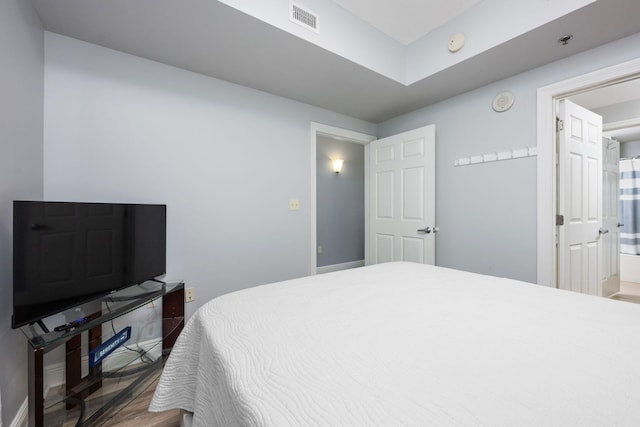 bedroom with wood finished floors, visible vents, and baseboards