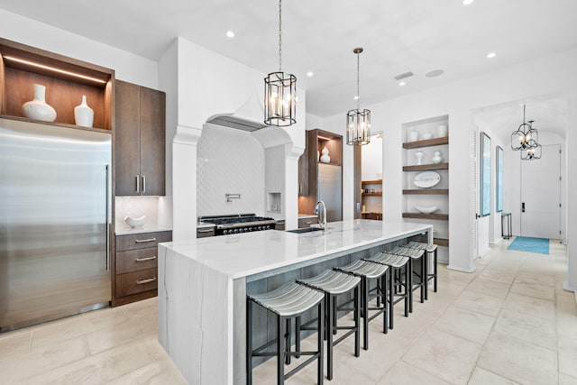 kitchen with arched walkways, modern cabinets, built in refrigerator, open shelves, and a sink