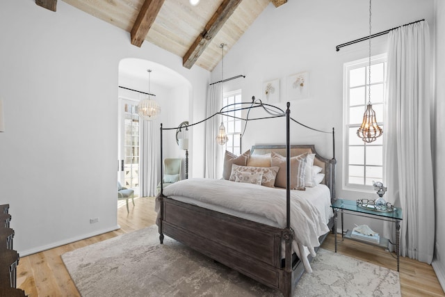 bedroom with arched walkways, wood ceiling, wood finished floors, high vaulted ceiling, and beam ceiling