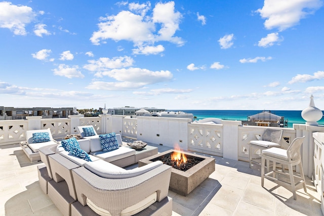 view of patio featuring a water view and an outdoor living space with a fire pit