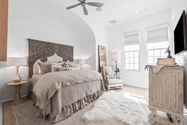 bedroom featuring a ceiling fan, lofted ceiling, visible vents, and wood finished floors