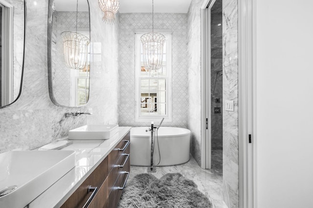 full bathroom featuring plenty of natural light, a soaking tub, vanity, a chandelier, and tile walls