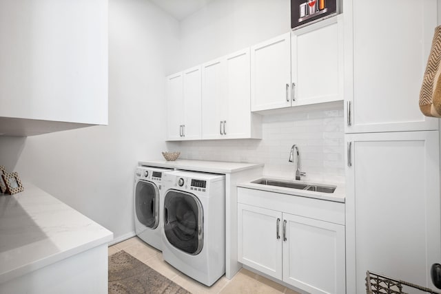 laundry room featuring light tile patterned floors, cabinet space, a sink, and separate washer and dryer