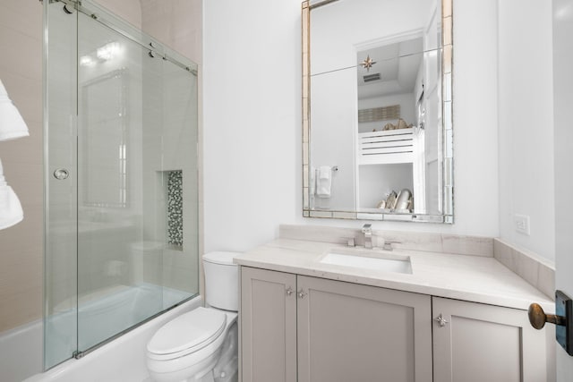 bathroom featuring combined bath / shower with glass door, vanity, and toilet