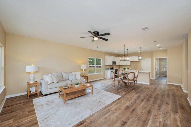 unfurnished living room featuring dark wood-style flooring, visible vents, a sink, ceiling fan, and baseboards