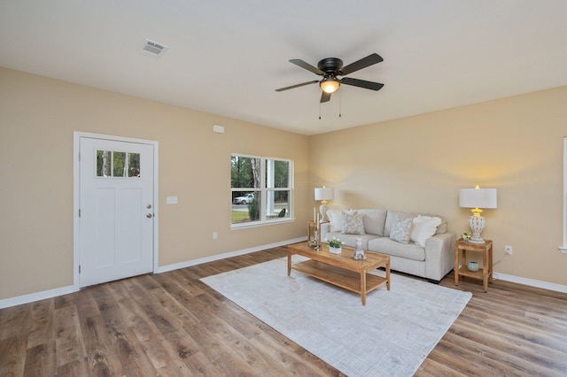 living area featuring light wood-style floors, visible vents, ceiling fan, and baseboards