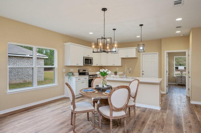 dining space with light wood-style flooring, visible vents, and baseboards