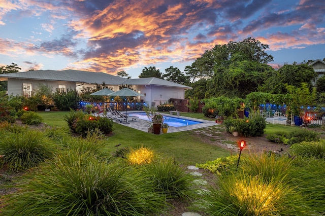 pool at dusk with a fenced in pool, a yard, a patio, and fence