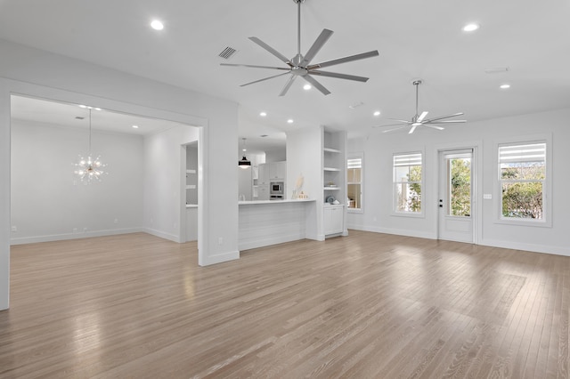 unfurnished living room with ceiling fan with notable chandelier, light wood-style flooring, visible vents, and recessed lighting