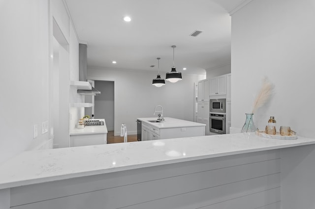 kitchen with an island with sink, ornamental molding, stainless steel appliances, a sink, and recessed lighting