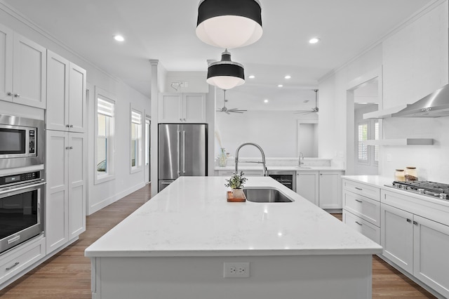 kitchen featuring appliances with stainless steel finishes, a sink, a kitchen island with sink, and white cabinets