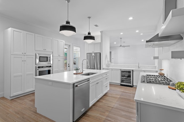 kitchen featuring wall chimney exhaust hood, beverage cooler, appliances with stainless steel finishes, and light countertops