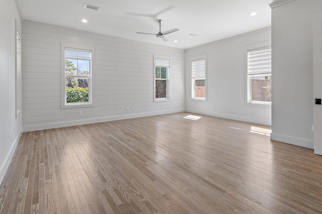 spare room with a healthy amount of sunlight, visible vents, and wood finished floors