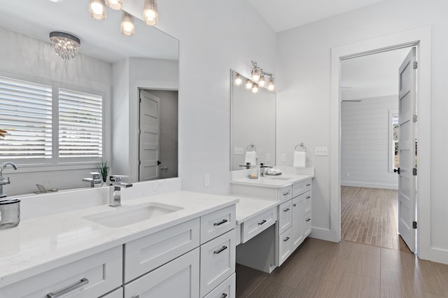 full bath with an inviting chandelier, vanity, and baseboards