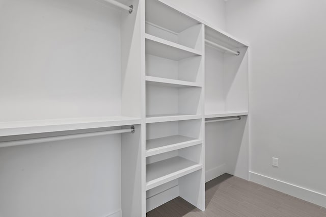 walk in closet with wood finished floors