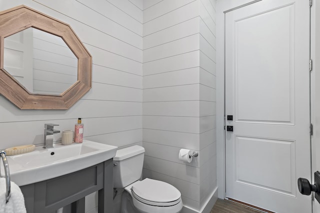 half bathroom with wood finished floors, a sink, and toilet