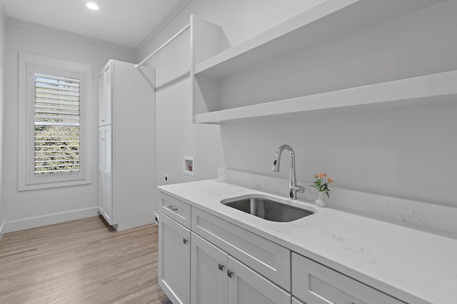 kitchen featuring light wood finished floors, ornamental molding, white cabinetry, open shelves, and a sink