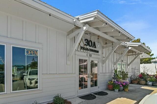 property entrance featuring board and batten siding and french doors