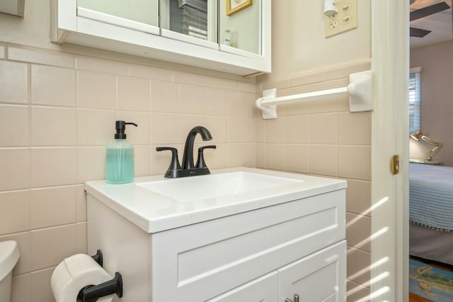 bathroom featuring vanity, toilet, and tile walls