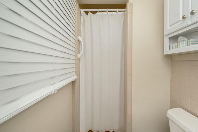 bathroom featuring tile walls and toilet