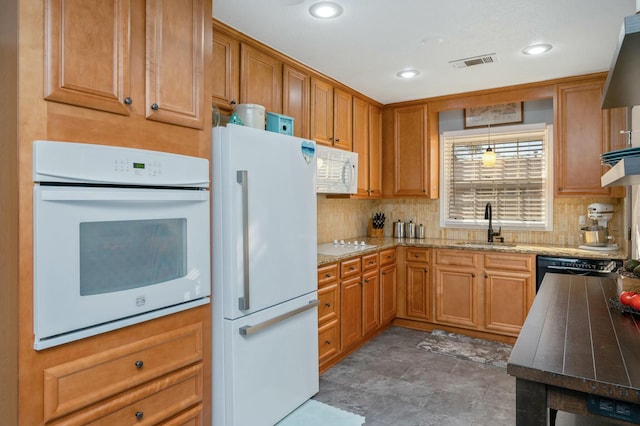 kitchen with white appliances, visible vents, decorative backsplash, brown cabinets, and a sink