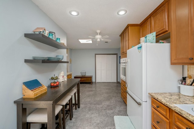 kitchen featuring light stone counters, white appliances, a ceiling fan, open shelves, and brown cabinetry