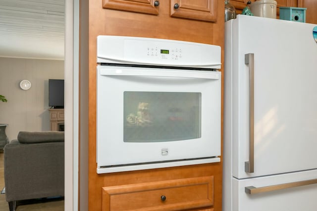 details with brown cabinetry, white appliances, and a fireplace