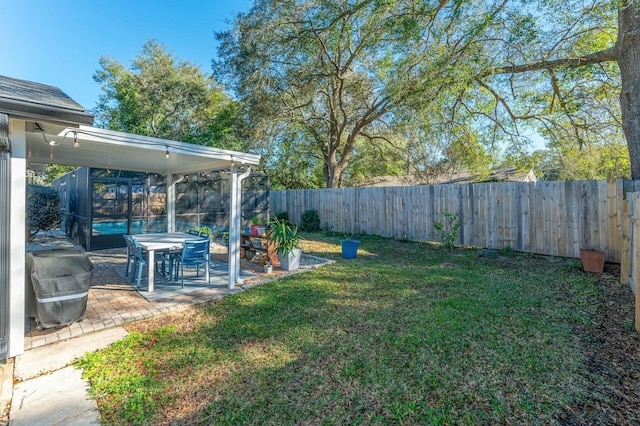 view of yard featuring glass enclosure, a fenced backyard, and a patio