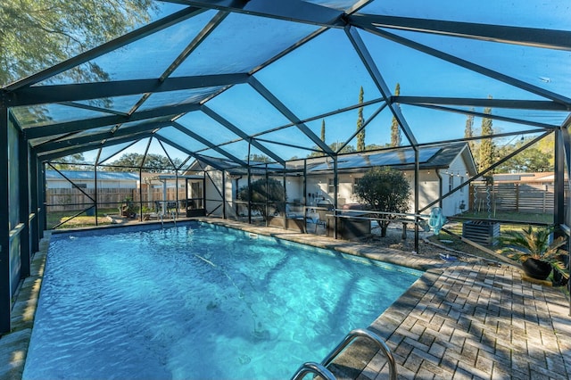 pool featuring glass enclosure, a fenced backyard, and a patio