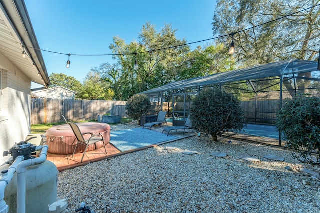 view of patio / terrace with a hot tub, glass enclosure, and a fenced backyard